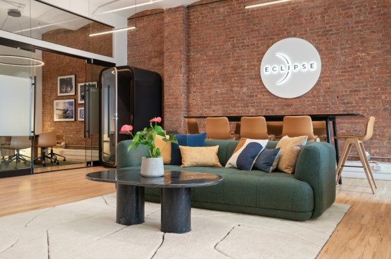 Image of Eclipse's new office that includes a green couch, glass coffee table and conference table.